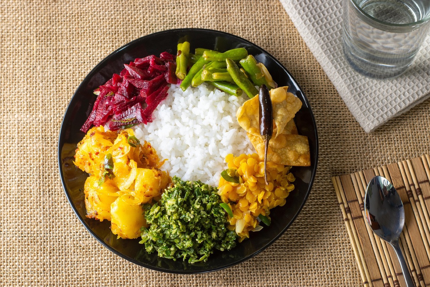 A plate of rice with dal, potatoes, greens and beetroot